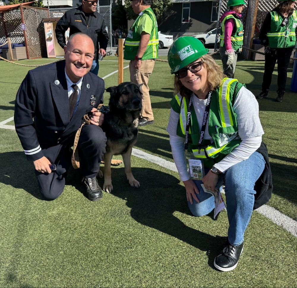 Uniformed firefighter and K-9 with NERT Volunteer in green vest and helmet