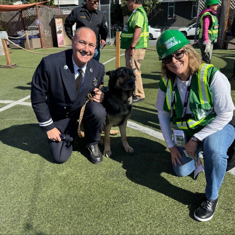 Uniformed firefighter and K-9 with NERT Volunteer in green vest and helmet